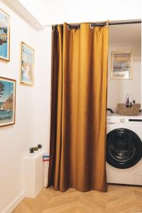 einen goldenen Duschvorhang in einem Zimmer mit Waschmaschine in der Unterkunft Le Petit Martray - Au coeur du centre ville in Lamballe