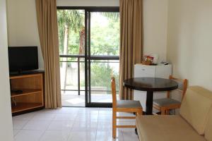 sala de estar con mesa, sofá y TV en Golden Suíte Hotel, en Campinas