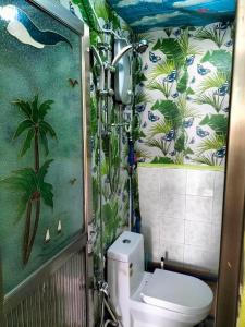 a bathroom with a toilet with a tropical wallpaper at Gracias Place in El Nido