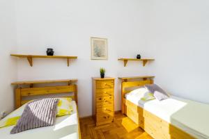 two beds in a room with white walls and wooden floors at Apartments Jonke in Mandre