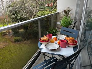 a table with food and drinks on a balcony at Spacieux studio sur jardin, beaucoup de charme in Boulogne-Billancourt