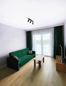 ヴロツワフにあるElegant 1-Bedroom Flat With Balcony Near Wrocławのリビングルーム(緑のソファ、テーブル付)