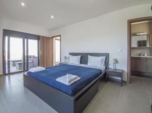 a bedroom with a large bed with a blue blanket at Modern villa with infinity pool close to the sea in Tavronitis