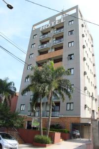 a tall building with a palm tree in front of it at Golden Suíte Hotel in Campinas