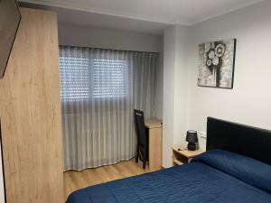 sypialnia z niebieskim łóżkiem i oknem w obiekcie HOSTAL CID w mieście Ourense