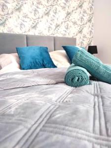 a bed with blue pillows and green towels on it at Apartament DanHouse in Giżycko