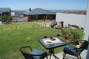 a table with two chairs and two glasses of wine at C-Vista in Stilbaai-Wes