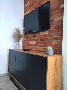 a flat screen tv on a brick wall with a tv stand at Apartament DanHouse in Giżycko