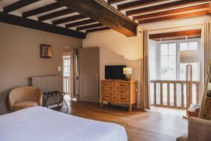 a bedroom with a bed and a television on a dresser at Le Château de la Roque Hôtels in Hébécrevon
