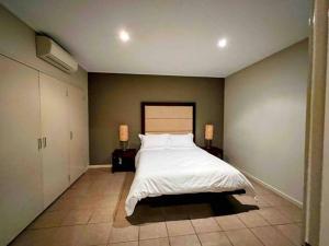 a bedroom with a white bed and two lamps at Modern 2 Bed Apartment - Oaks Resort, Cable Beach in Cable Beach