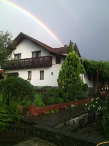 um arco-íris sobre uma casa branca com um jardim em Apartvilla Serbota em Porumbacu de Sus