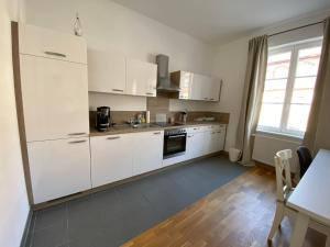 拜羅伊特的住宿－Wohnung in Bayreuths schönster Straße，白色的厨房配有白色的橱柜和桌子