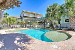 a swimming pool in front of a house with palm trees at Beachy Keen in Port Aransas