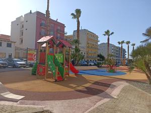 um parque infantil numa cidade com palmeiras e edifícios em A Casa di Franco em Milazzo