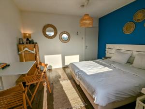 een slaapkamer met een blauwe muur, een bed en een bureau bij Budget Hotel Vrouwenpolder in Vrouwenpolder