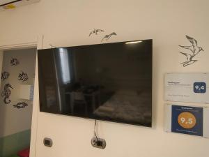 einen Flachbild-TV, der an einer Wand hängt in der Unterkunft Blue Rose Private Room in Salerno