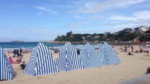 un groupe de parasols bleus et blancs sur une plage dans l'établissement Joli T2 à Dinard coeur de Saint Enogat, 200m de la plage, à Dinard 4 autres photos