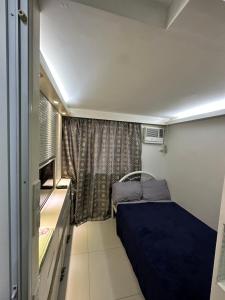 een kleine kamer met een bed en een raam bij Grand Riviera Suits in Manilla