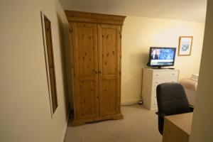 a room with a wooden closet and a television at Bellengers Bee in Kidlington