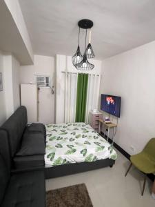 a bedroom with a bed and a couch and a television at Grand Residences Studio Unit - Walking Distance to IT Park in Cebu City