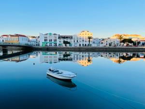 a small boat in the water in front of buildings at Central Tavira apartment with balcony, Casa Cristina in Tavira