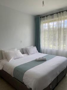 1 cama grande en un dormitorio con ventana en Zoe Homes 1br and 2br Apartment Greypoint 406, en Kericho