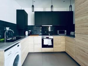 a kitchen with black cabinets and a white dishwasher at Neils Place hosted by AirOperate in London