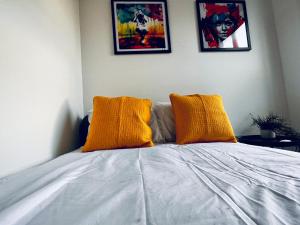 uma cama com duas almofadas amarelas em cima em Neils Place hosted by AirOperate em Londres