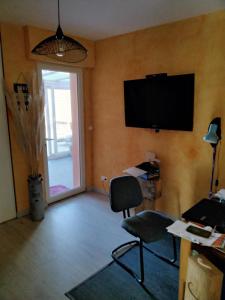 a room with a chair and a television on a wall at La pause ô logis gourmande in Navarrenx