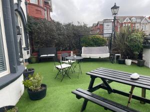 a patio with a picnic table and chairs on grass at North Crest in Blackpool