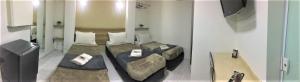 a room with two beds and a table in it at Hotel Malka in São Paulo