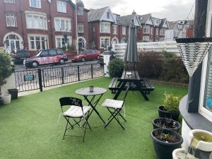 um pátio com uma mesa, cadeiras e um guarda-sol em North Crest em Blackpool