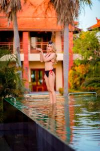 Nakara Villas & Glamping Udon Thani في أودون ثاني: امرأة ترتدي البيكيني تقف بجوار حمام السباحة