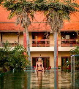 Nakara Villas & Glamping Udon Thani في أودون ثاني: امرأة في البيكيني تقف في جسم من الماء