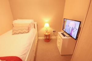 a bedroom with a bed and a flat screen tv at Bellengers Apartments in Kidlington