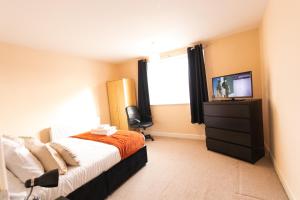 um quarto com uma cama e uma televisão em Bellengers Apartments em Kidlington