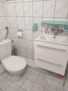 a bathroom with a white toilet and a sink at Pokoje gościnne Cuma in Łeba