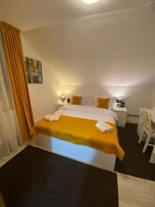 ブラショヴにあるPensiunea Tinelu Brașov saceleのベッドルーム1室(大型ベッド1台、黄色い毛布付)
