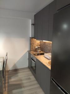 a kitchen with black cabinets and a sink at Bruklinas in Šiauliai