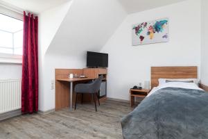 Schlafzimmer mit einem Bett, einem Schreibtisch und einem TV in der Unterkunft Hotel am Ludwigsplatz in Gießen