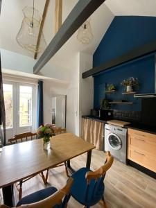 cocina con mesa de madera y paredes azules en Maisonnette,100m mer, proche St Malo/Cancale, WIFI, en Saint-Benoît-des-Ondes