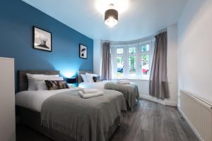 two beds in a room with blue walls at Accessible 3-bedroom bungalow with patio +driveway in Southampton
