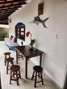 una sala da pranzo con tavolo e sgabelli in legno di Casa Aconchegante ao Pé da Praia do Portinho a Ilhabela