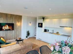 a living room with a couch and a kitchen with a fireplace at 't Soute Land in Zoutelande