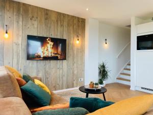 a living room with a couch and a tv on a wall at 't Soute Land in Zoutelande