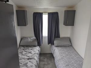 um pequeno quarto com 2 camas e uma janela em Static Caravan on Lady's Mile Holiday Park em Dawlish