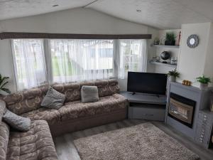 uma sala de estar com um sofá e uma televisão em Static Caravan on Lady's Mile Holiday Park em Dawlish