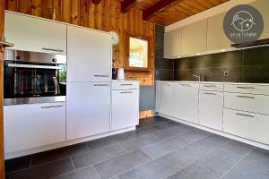 a kitchen with white appliances and wooden walls at Chalet Cassiopée in Ovronnaz