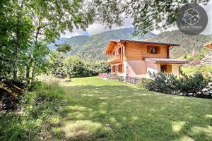 ein Haus mit einem Rasenplatz vor einem Haus in der Unterkunft Chalet Cassiopée in Ovronnaz