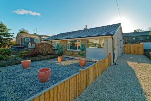 a home with a fence and potted plants in a yard at Modern, but cosy Bungalow in Queensbury